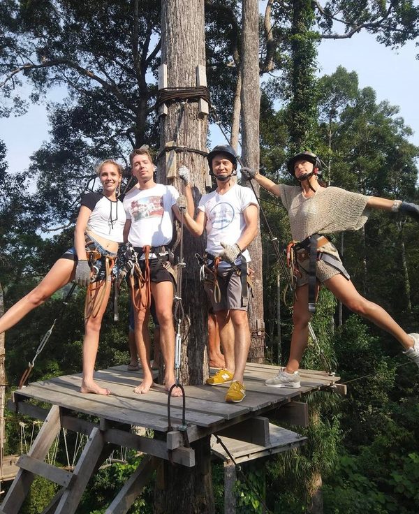 Group of four in safety harnesses and helmets on a zipline platform in the jungle, Koh Phangan